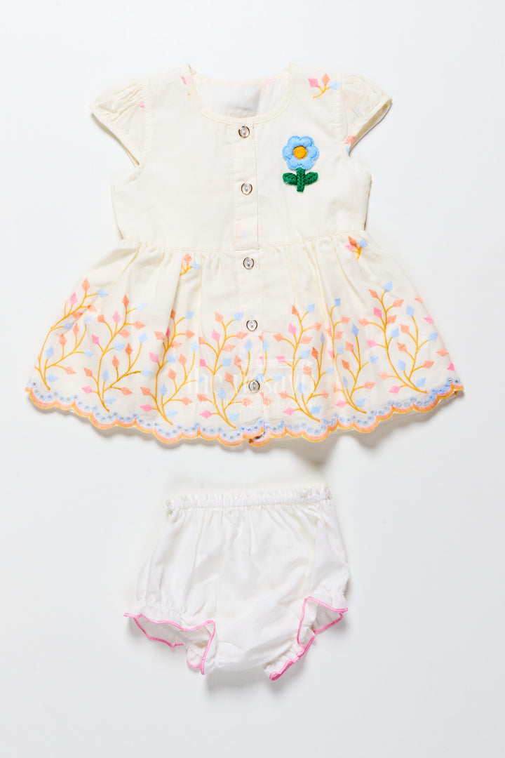 White baby frock with pastel floral embroidery and ruffled hem