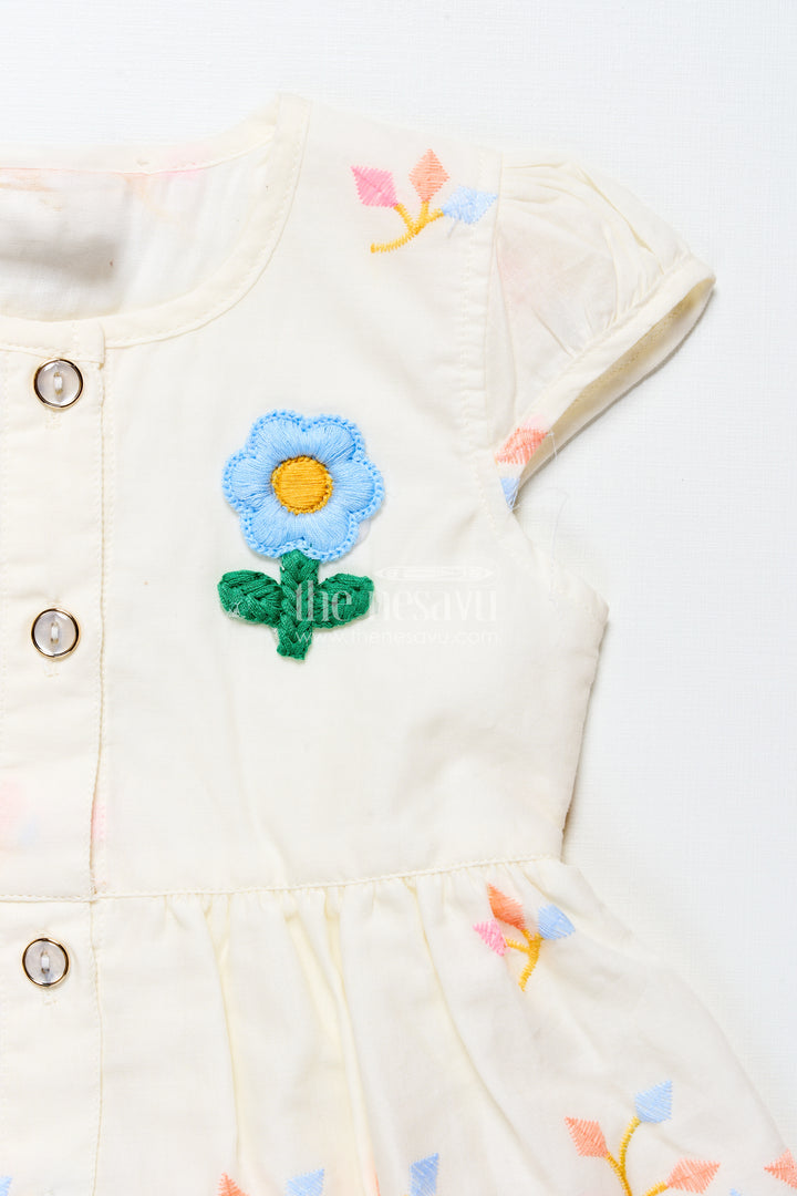 White baby frock with pastel floral embroidery and ruffled hem