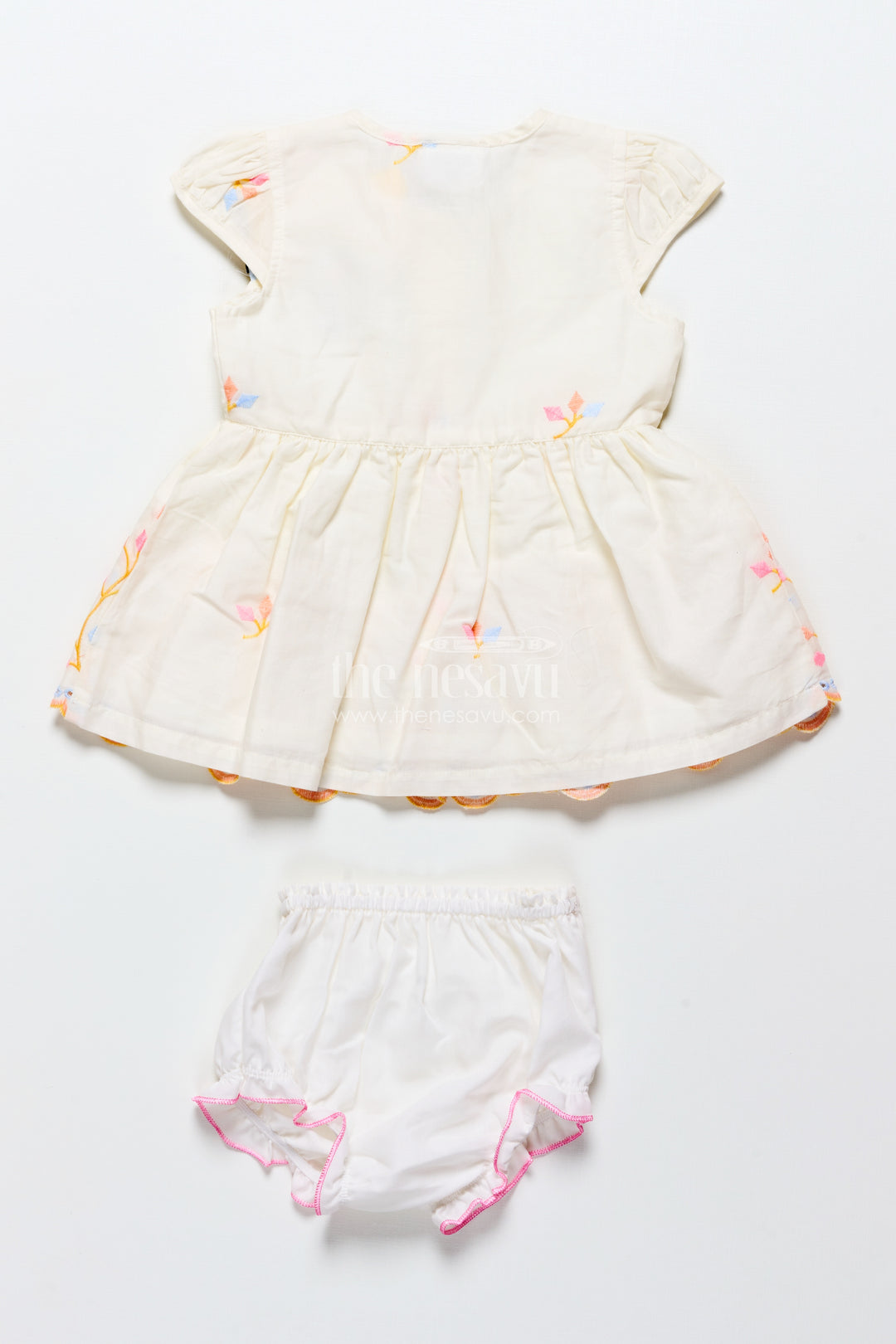 White baby frock with pastel floral embroidery and ruffled hem