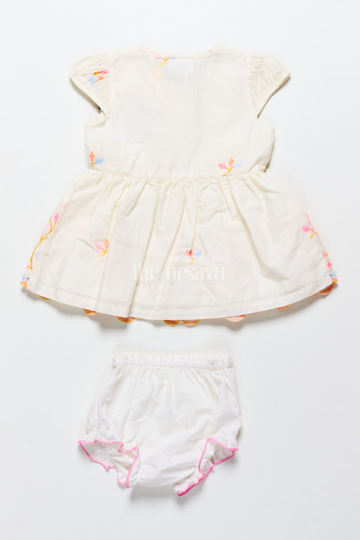 White baby frock with pastel floral embroidery and ruffled hem
