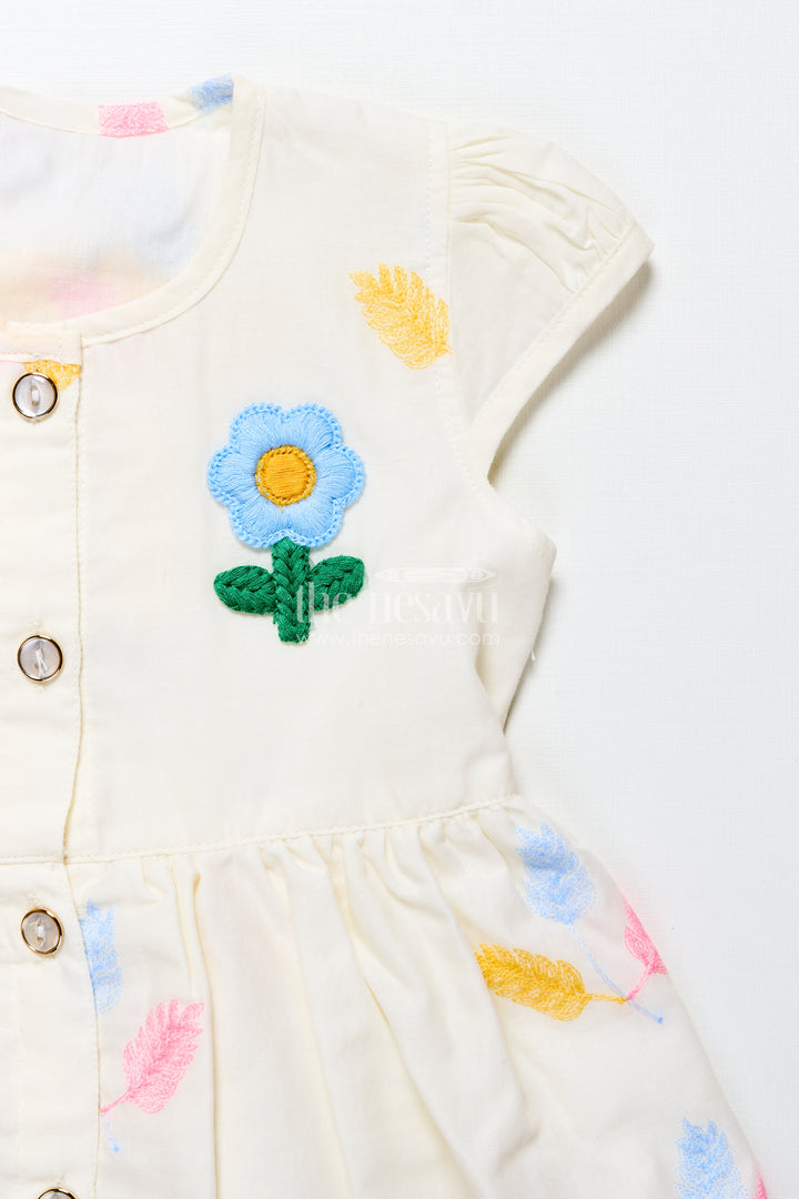 Cream baby frock with pastel thread embroidery and flower patch
