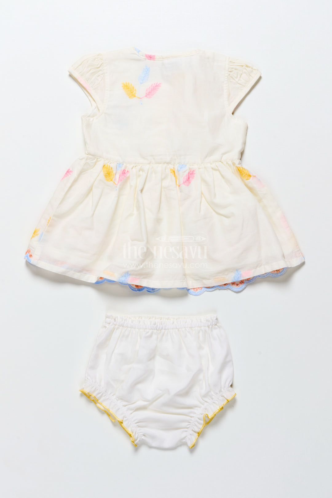 Cream baby frock with pastel thread embroidery and flower patch