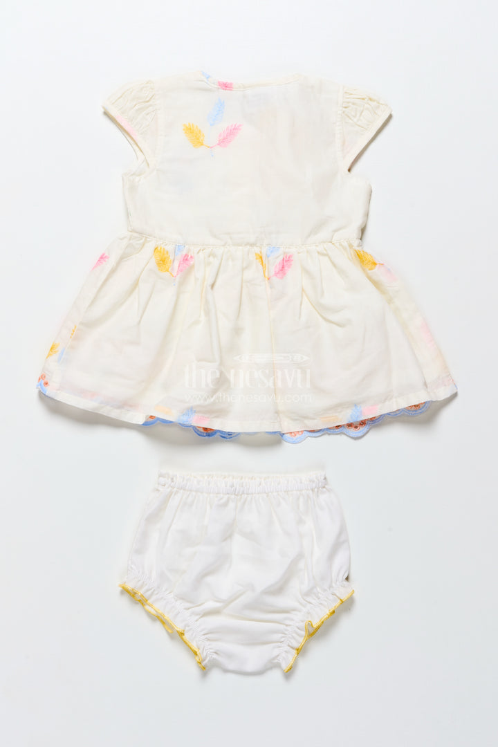 Cream baby frock with pastel thread embroidery and flower patch
