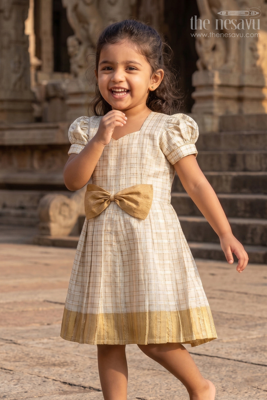 Girls Short Frocks for Party in Beige Silk with Gold Bow Embellishment and Checked Pleated Design
