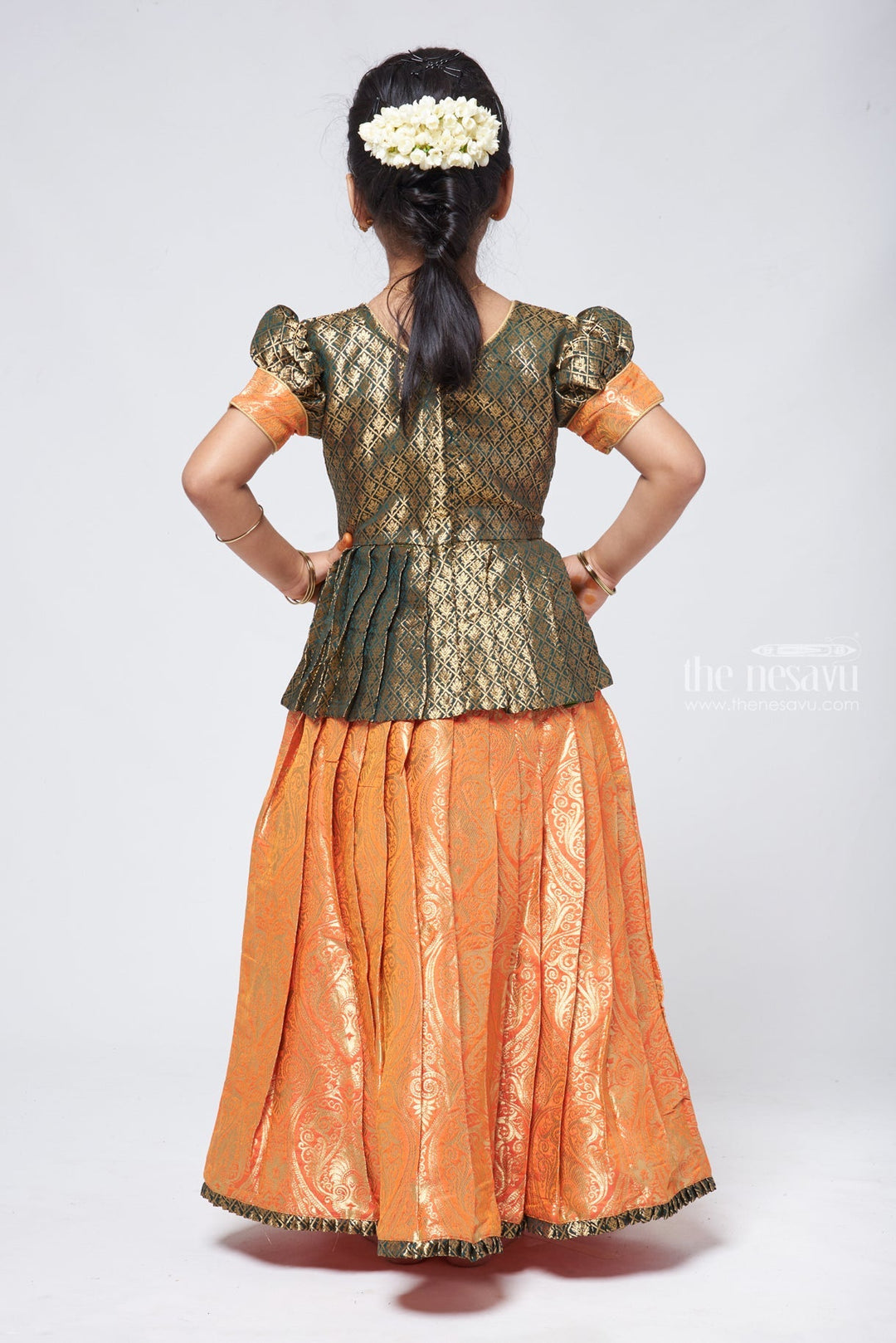 The Nesavu Pattu Pavadai Elegant Brocade Peplum Green Blouse paired with Banarasi Salmon Pink Pattu Pavadai: Timeless South Indian Nesavu Elegant Brocade Designer Pattu Pavadai for Girls | Banaras Silk Pattu Pavadai | The Nesavu