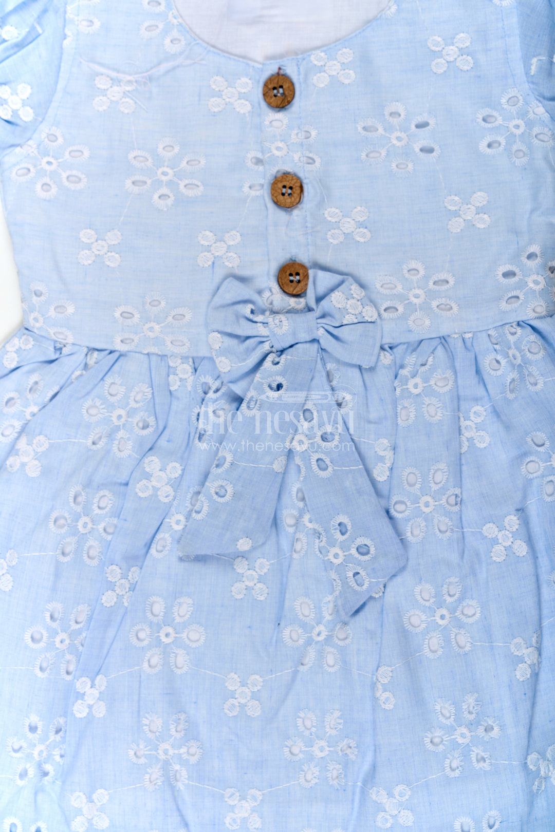 The Nesavu Girls Cotton Frock Girls Casual Wear Party Dress in Sky Blue Hakoba with Bow Belt and Wooden Button Detail Nesavu Nesavu Casual Wear Party Dress for Girls in Sky Blue Hakoba with Embroidery and Waist Bow