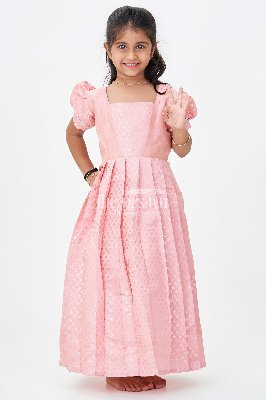 The Nesavu Girls Silk Gown Girls Semi Banaras Silk Pink Party Wear Gown with Intricate Woven Motifs and Classic Puff Sleeves Nesavu Girls Semi Banaras Silk Pink Party Wear Gown Floral Woven Design Puff Sleeves | The Nesavu